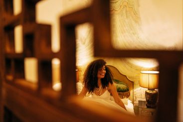 Cute African sitting on the bed and smiling in a hotel...