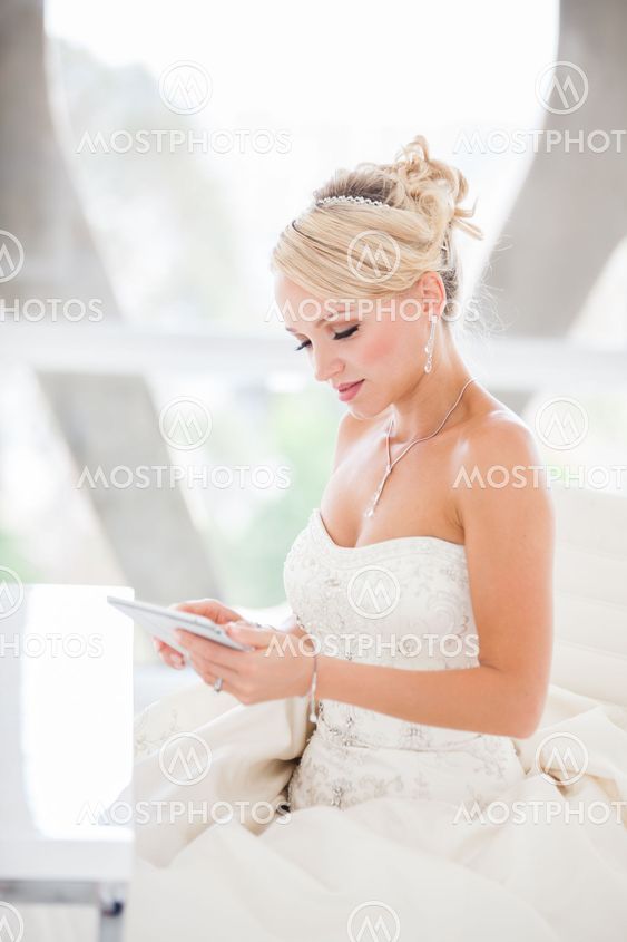 Smiling beautiful blond bride sitting at a table with a Mini touch pad