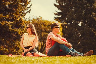 Moody girl with boyfriend in park. 