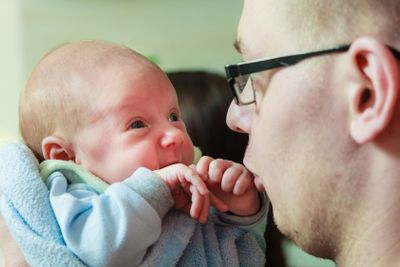 Father holding little newborn baby in blanket