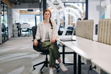 A modern businesswoman with striking orange hair sitting...