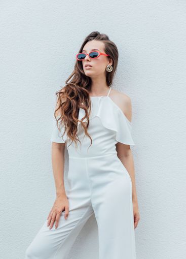 Beautiful brunette woman in white suit posing by the...