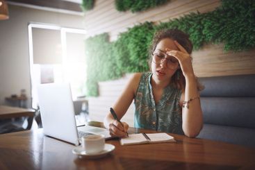 Woman, stress and writing in notebook at coffee shop...