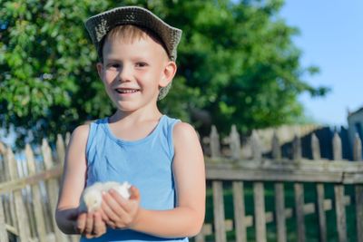 Young Boy Holding His Chick While at the Garden