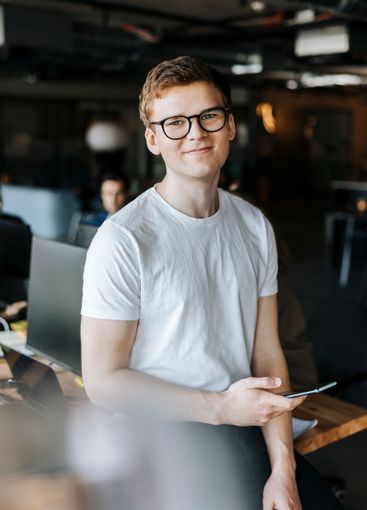 Portrait of smiling young tech entrepreneur with smart...