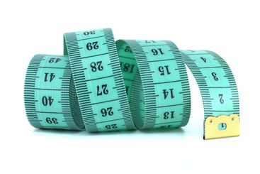 A light green measuring tape curled on a white...