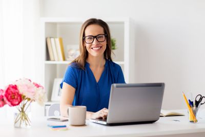 happy woman with laptop working at home or office