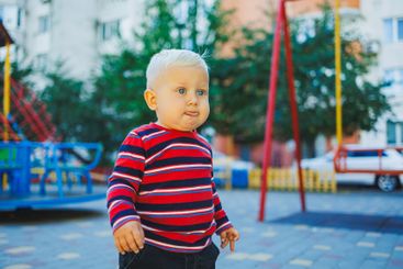A fair-haired one-year-old boy in jeans and sneakers...