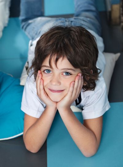 Boy With Head In Hands Lying On Floor In Preschool