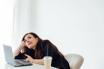 woman brunette sitting at desk tired online laptop