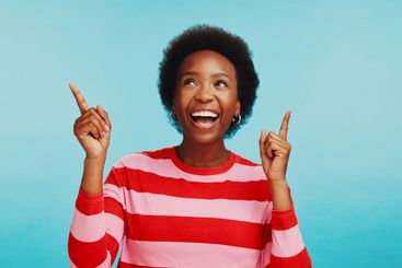 Black woman, pointing up and smile for advertising,...