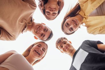 Funny smiling teenagers standing and looking down at camera