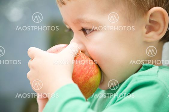 Little child is biting red apple and smile
