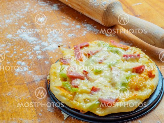 Pizza on a wooden table sprinkled with flour.