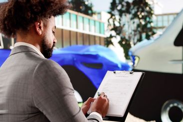 African American Insurance Agent Inspects Car Damage After