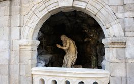 Stone statue in a grotto surrounded by an arched stone...