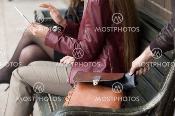 Thief stealing wallet from woman sitting on a bench
