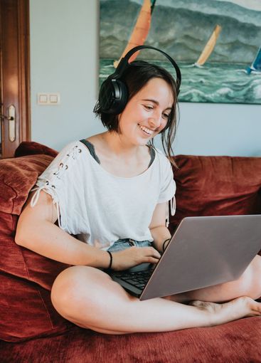 Happy young woman in a relaxed cloth works at home on a...