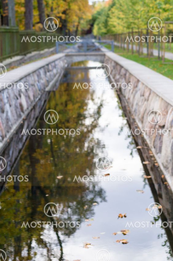 Defocused image of canal with autumnal trees reflection in water