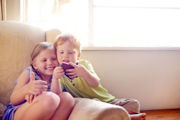 Fun, siblings and children with smartphone, relax and...