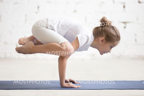 Girl child in Bakasana pose, white studio background