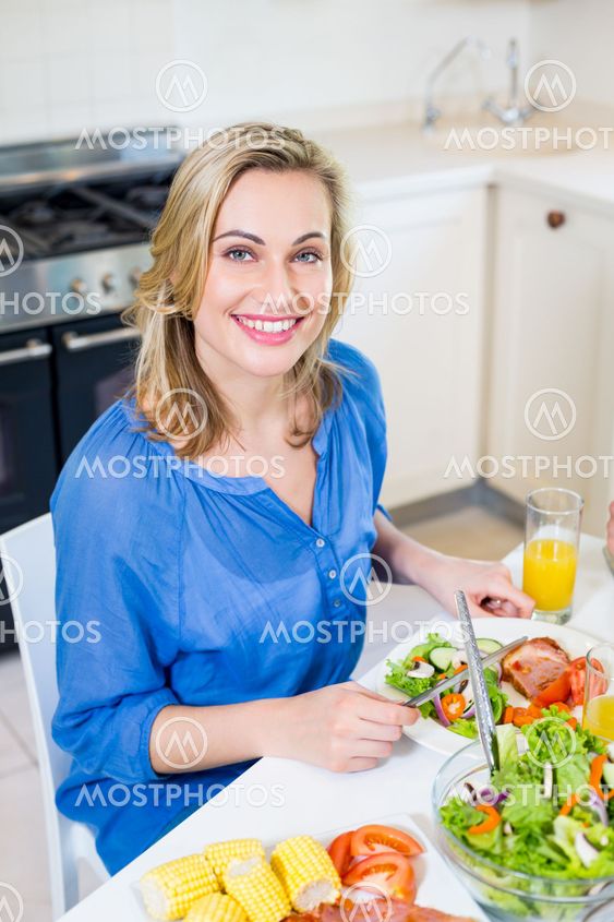 Young woman sitting at dining table smiling