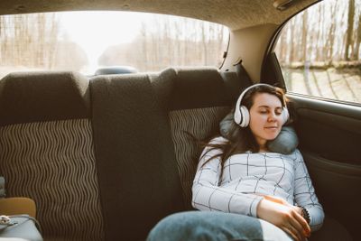 woman sitting at car backseats and listening music. car...