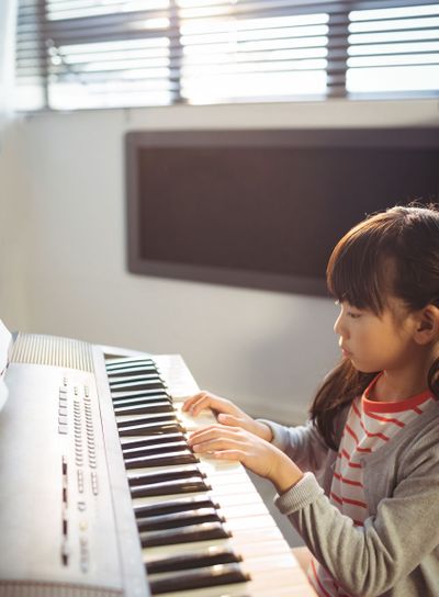 High angle view of concentrated girl practicing piano in...