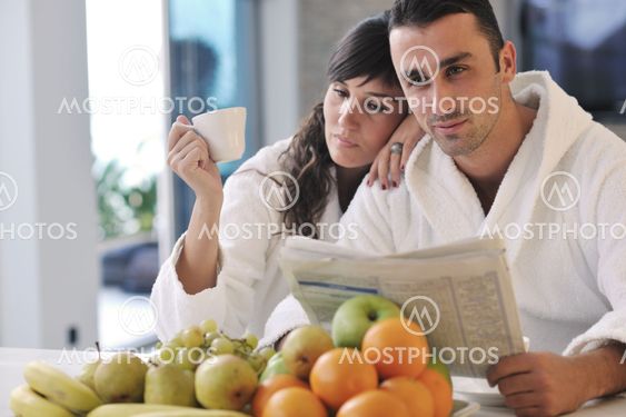 Happy couple reading the newspaper in the kitchen at breakfast