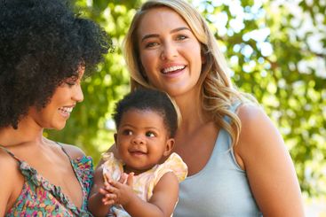 Loving Same Sex Female Couple Or Friends Cuddling Baby...