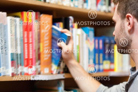 Handsome male student picking a book