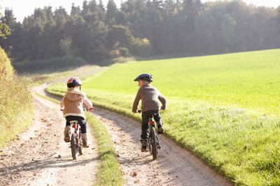 Two young children ride bicycles in park