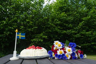 Svensk sommarbild med tårta, blommor och flagga