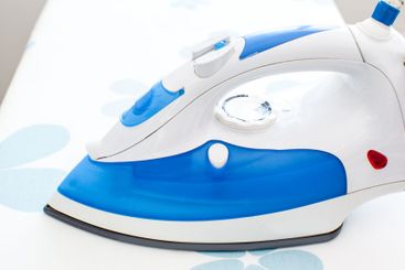 Iron on ironing board on light home interior background