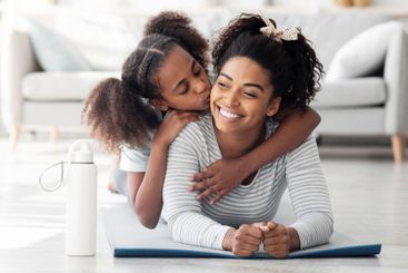 Happy black mother and daughter cuddling while...