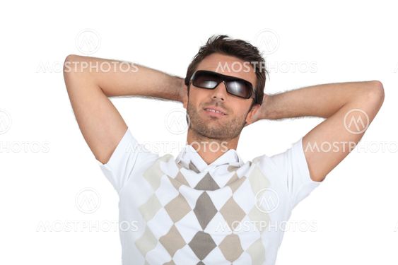 Man wearing sunglasses with his hands behind his neck