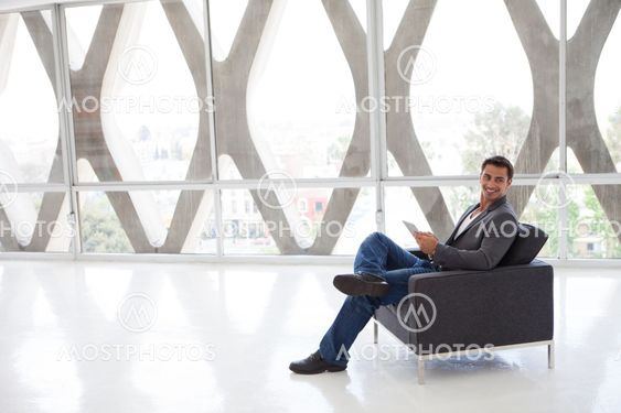 Happy good looking man in his 20s working on a mini think pad