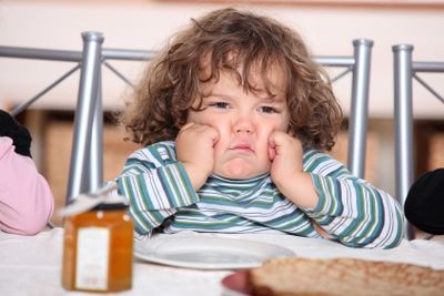 little boy grouching in front a plate of crepes