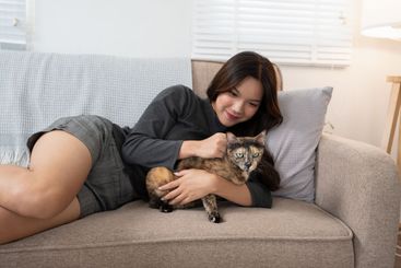 A woman lying on a couch, lovingly cuddling with her...
