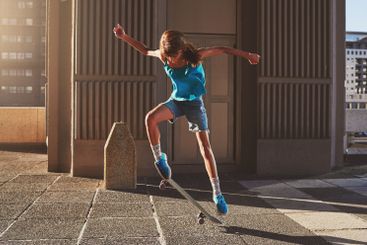 Skateboard, city and woman with trick in air for jump...