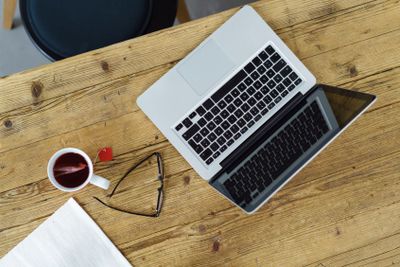 Open laptop with a cup of tea and eyeglasses