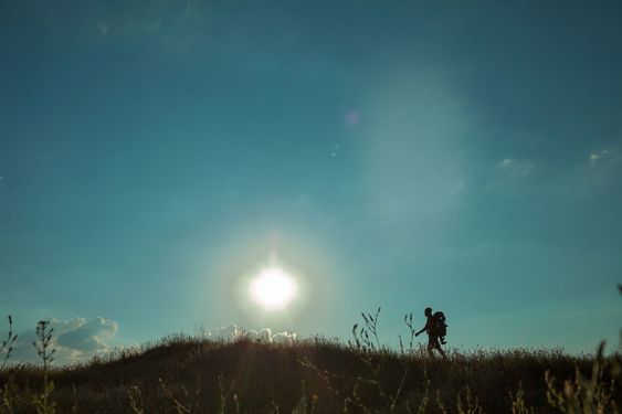 Young caucasian man with backpack walking on a green meadow