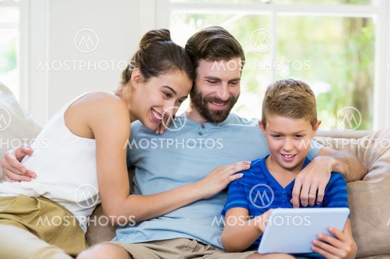 Parents and son using digital tablet in living room