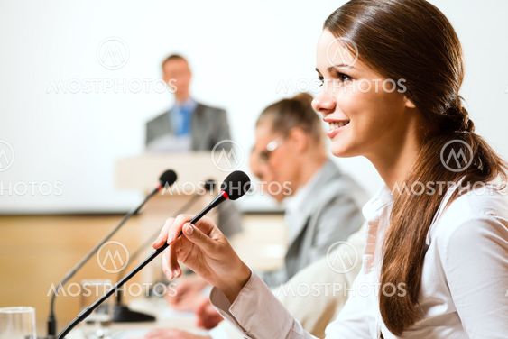 Business woman speaks into a microphone