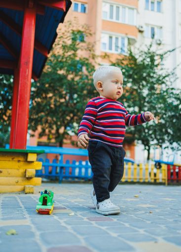 A fair-haired one-year-old boy in jeans and sneakers...