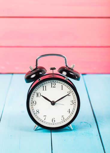 Black vintage alarm clock on wooden table
