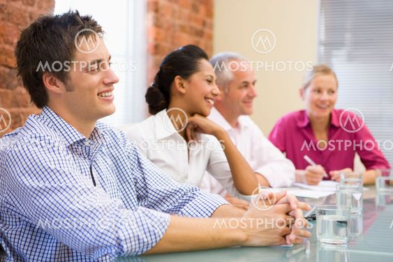 Four businesspeople in boardroom smiling
