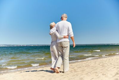 happy senior couple hugging on summer beach