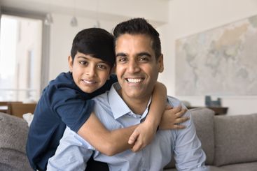 Home portrait of Indian man and son posing camera
