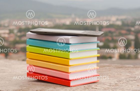 Stack of colorful books with electronic book reader